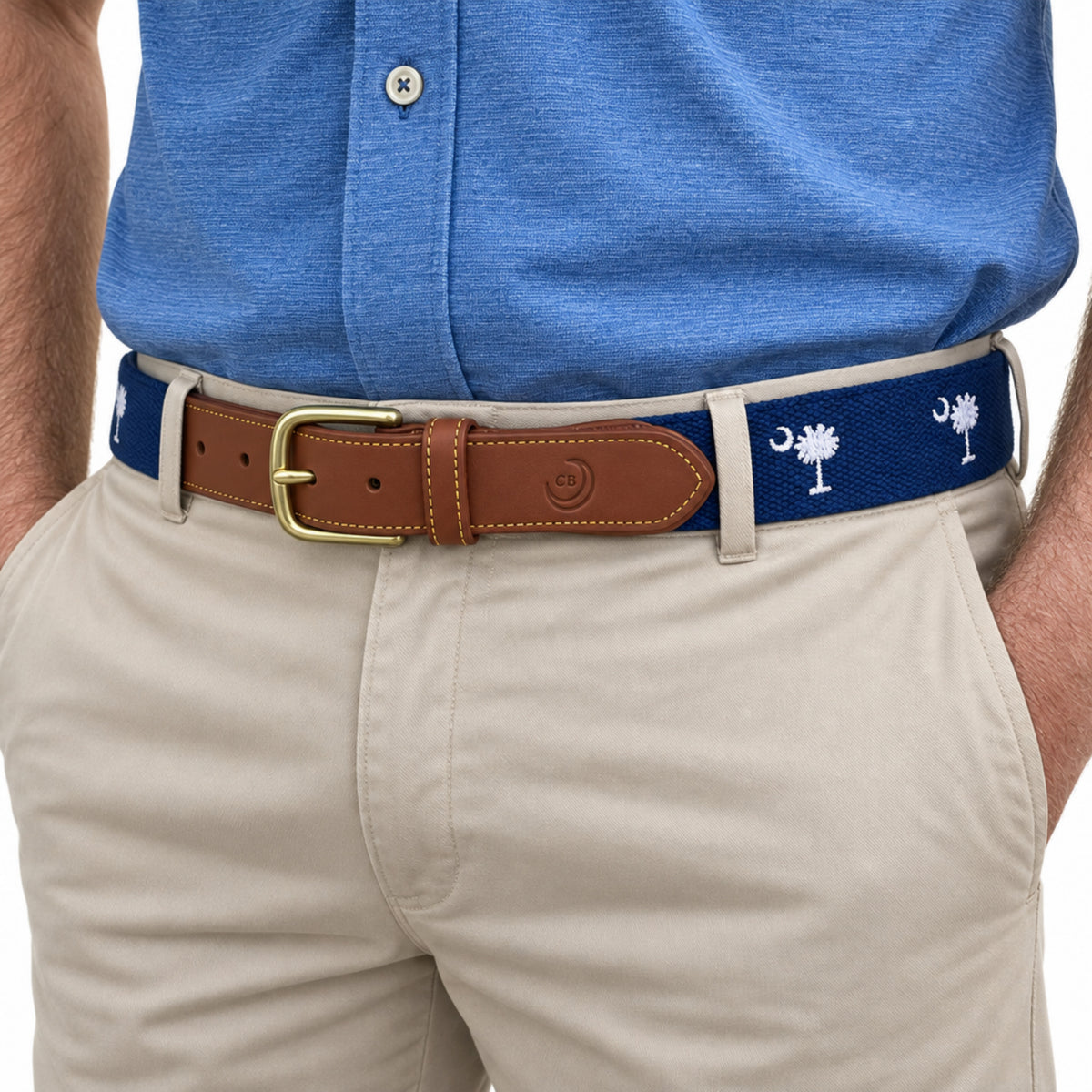 A close-up of a man wearing a blue South Carolina flag belt with a brown leather strap and buckle, paired with a blue polo shirt and khaki pants.