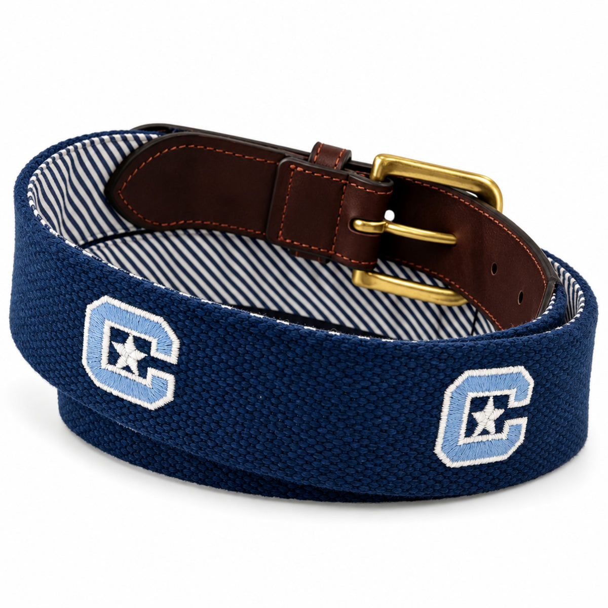 A navy blue woven belt with a brown leather buckle loop, gold-tone metal buckle, and a striped fabric lining. The belt features two embroidered light blue and white 'C' logos with white stars on the front.