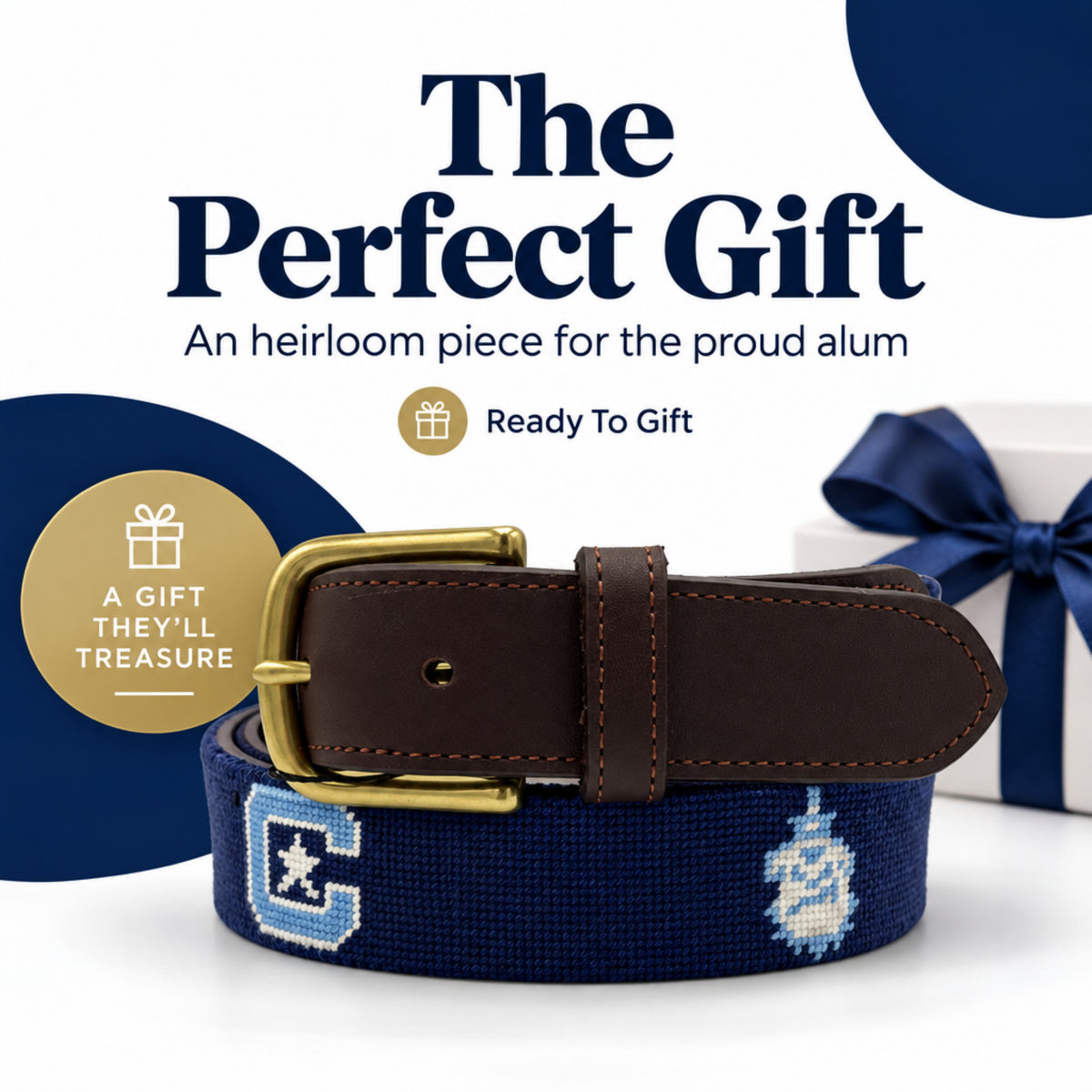 A navy blue needlepoint belt with a brown leather strap and gold buckle, displayed on a white background with a wrapped gift box and promotional text.
