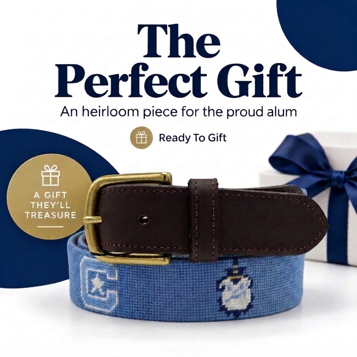 A blue needlepoint belt with insignia for The Citadel Bulldogs with a dark brown leather finishing and gold-tone buckle, displayed on a white surface with a wrapped gift box and promotional text reading 'The Perfect Gift' and 'Ready To Gift'.