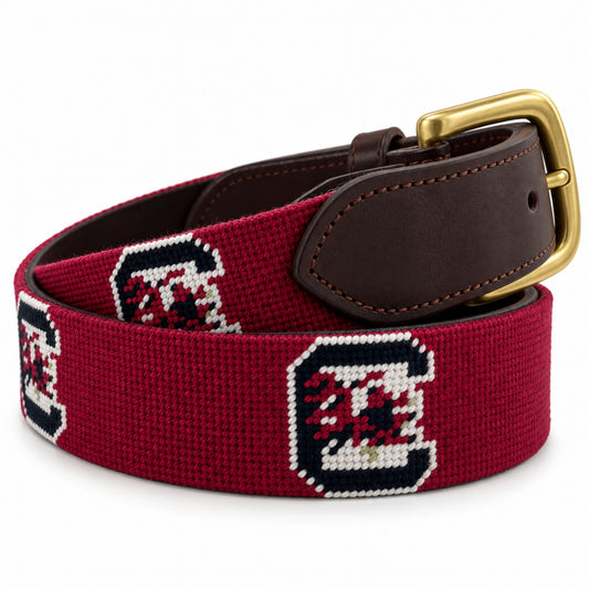 A navy and red embroidered needlepoint belt with dark brown leather finishing and a brass buckle, featuring the South Carolina Gamecocks logo.