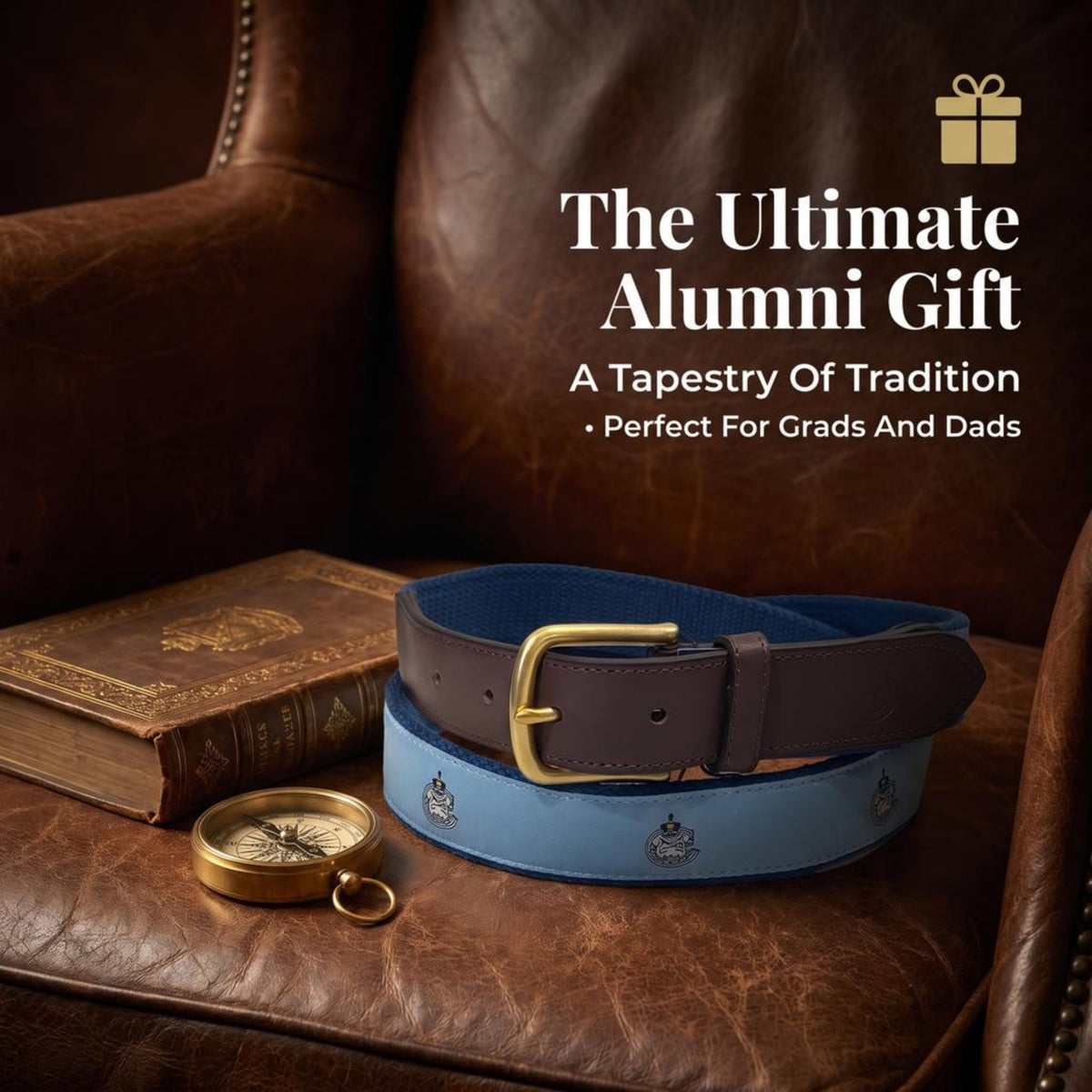 A leather belt displayed on a brown leather armchair with a vintage book and compass nearby. The belt has dark brown  leather with a gold buckle, and the belt is light blue with The Citadel Bulldogs mascot Spike.