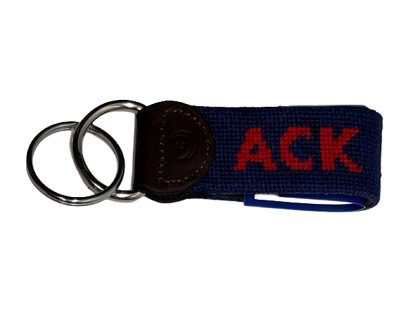 hand-stitched needlepoint key fob with navy blue base color and bright red ACK text.  finished in dark brown genuine leather and solid "D" ring and key chain in silver color chrome/nickel